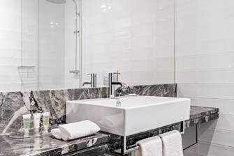 Badezimmer mit Waschbecken, Spiegel, Dusche, Pflegeprodukten