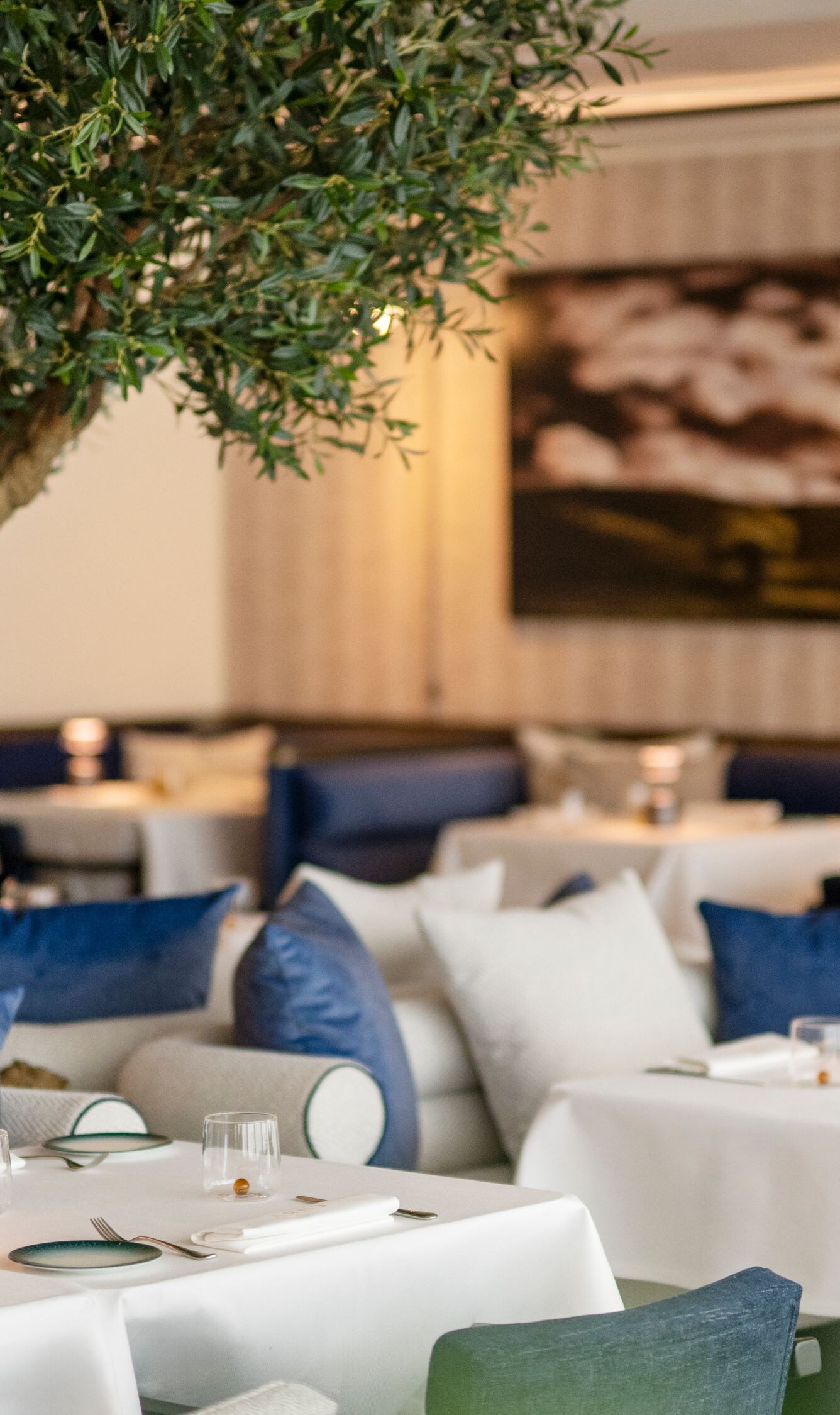 Chic dining room configuration featuring plush banquettes and design tree accents.
