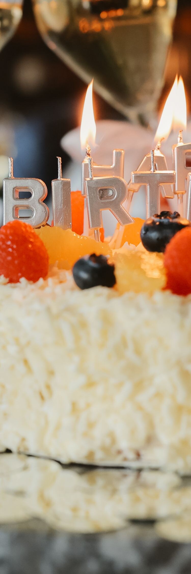 Clinking champagne glasses over a glowing cake.