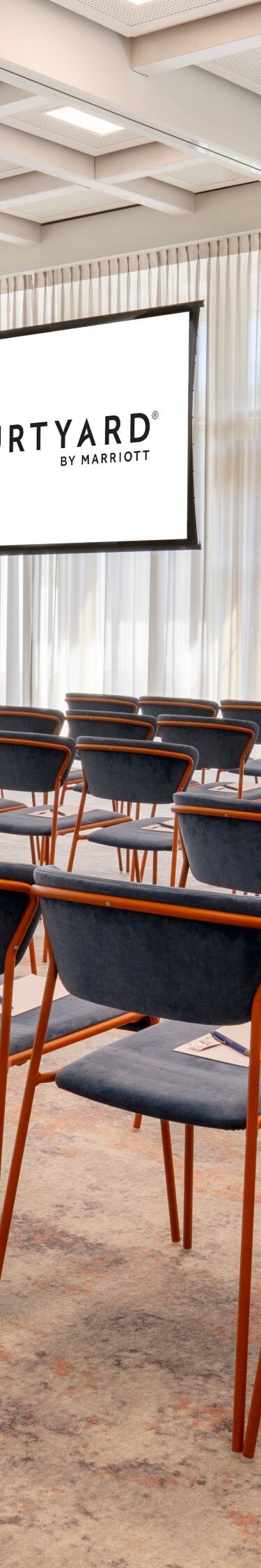 Multi-screen presentation hall set with theater-style row seating.