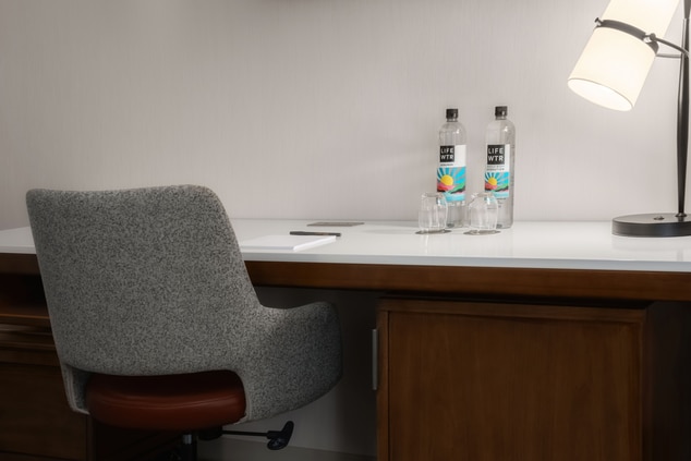 Desk, water bottles, and grey chair.