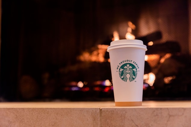 Cup of hot Starbucks coffee in front of fireplace 