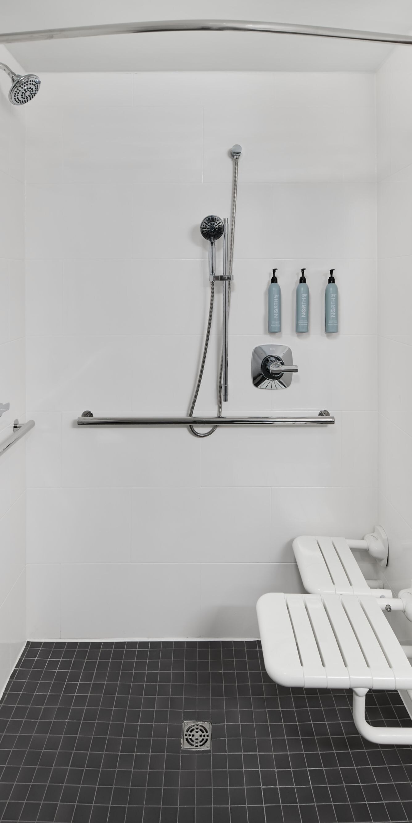 Roll‑in shower with grab bars and fold‑down seat
