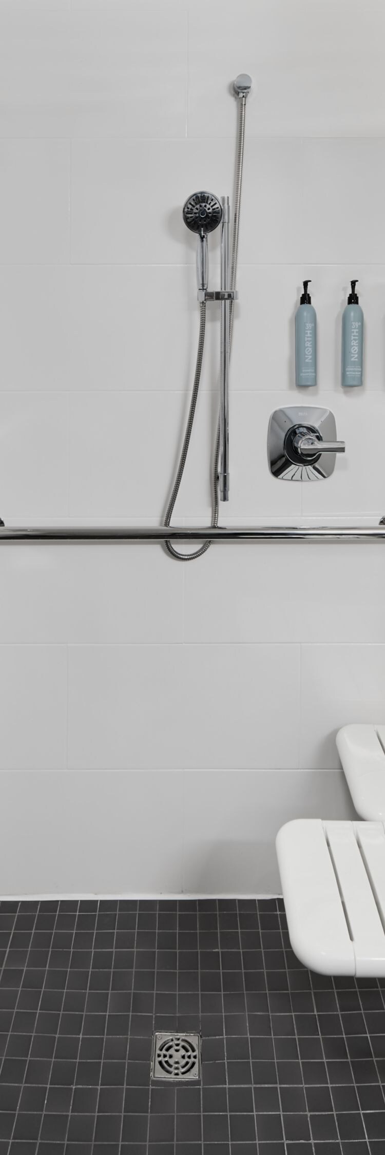 Roll‑in shower with grab bars and fold‑down seat