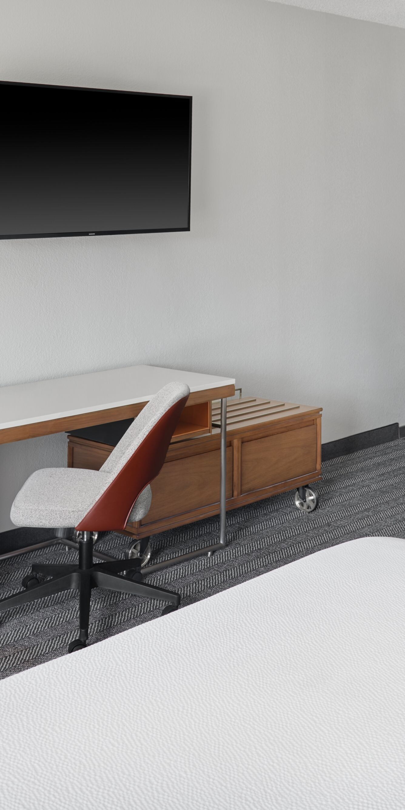 Two beds with long desk, chair, wall‑mounted TV