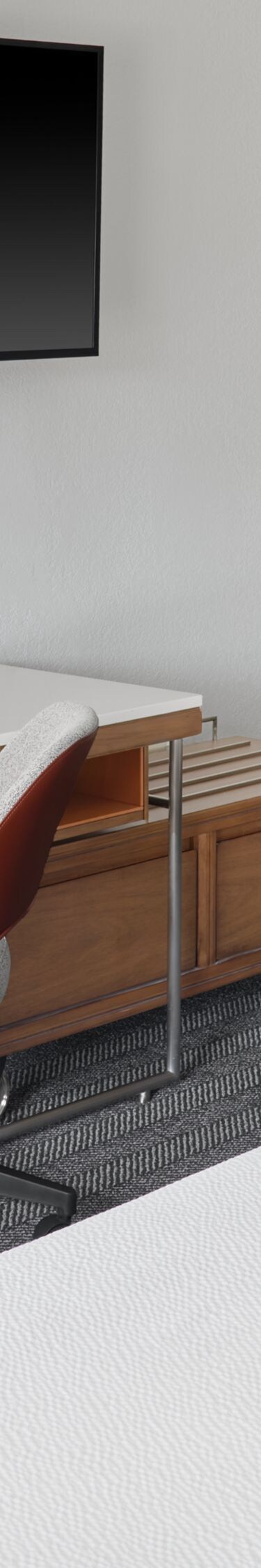 Two beds with long desk, chair, wall‑mounted TV
