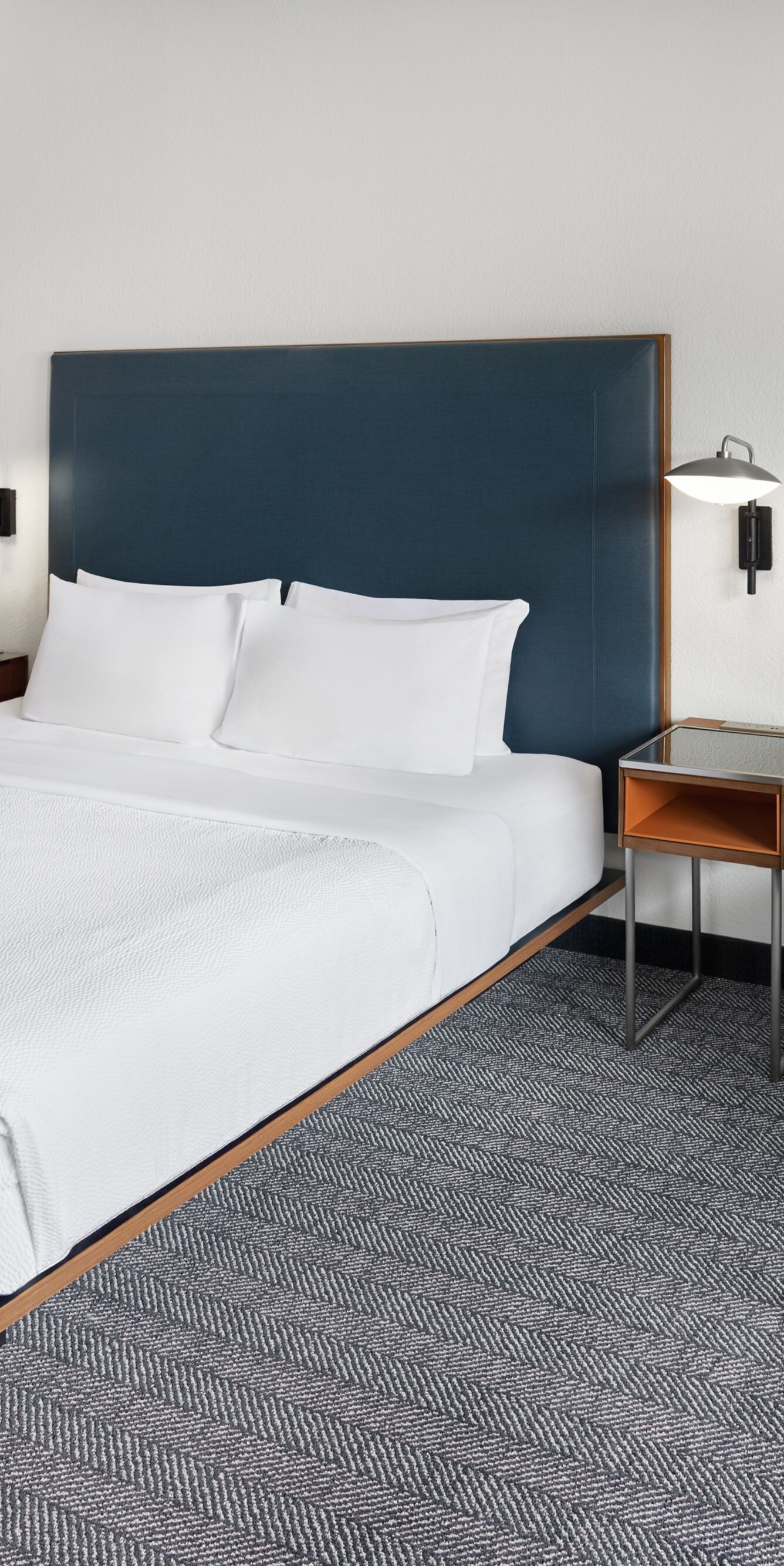 king bed, orange armchair, ottoman, and lamp