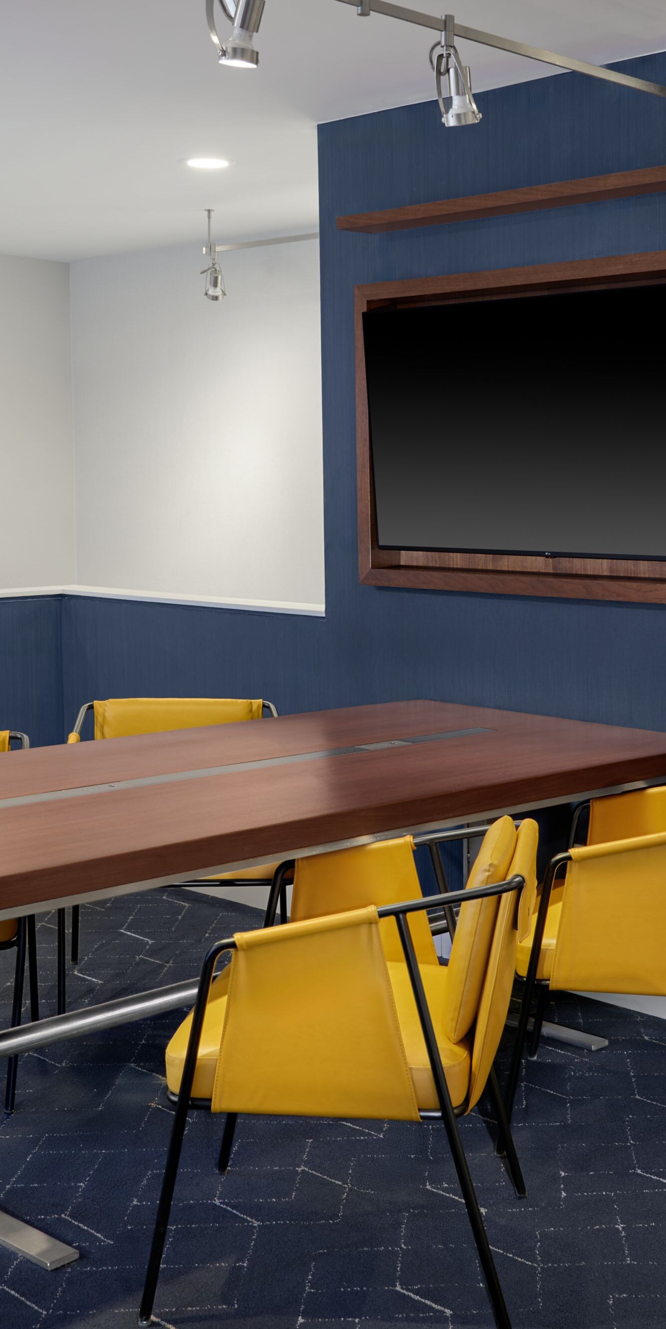 Meeting table with yellow chairs and wall‑mounted 