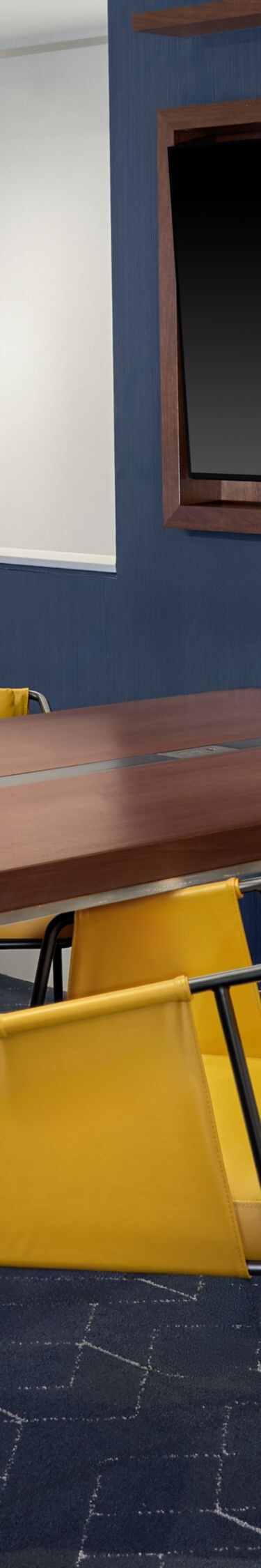 Meeting table with yellow chairs and wall‑mounted 