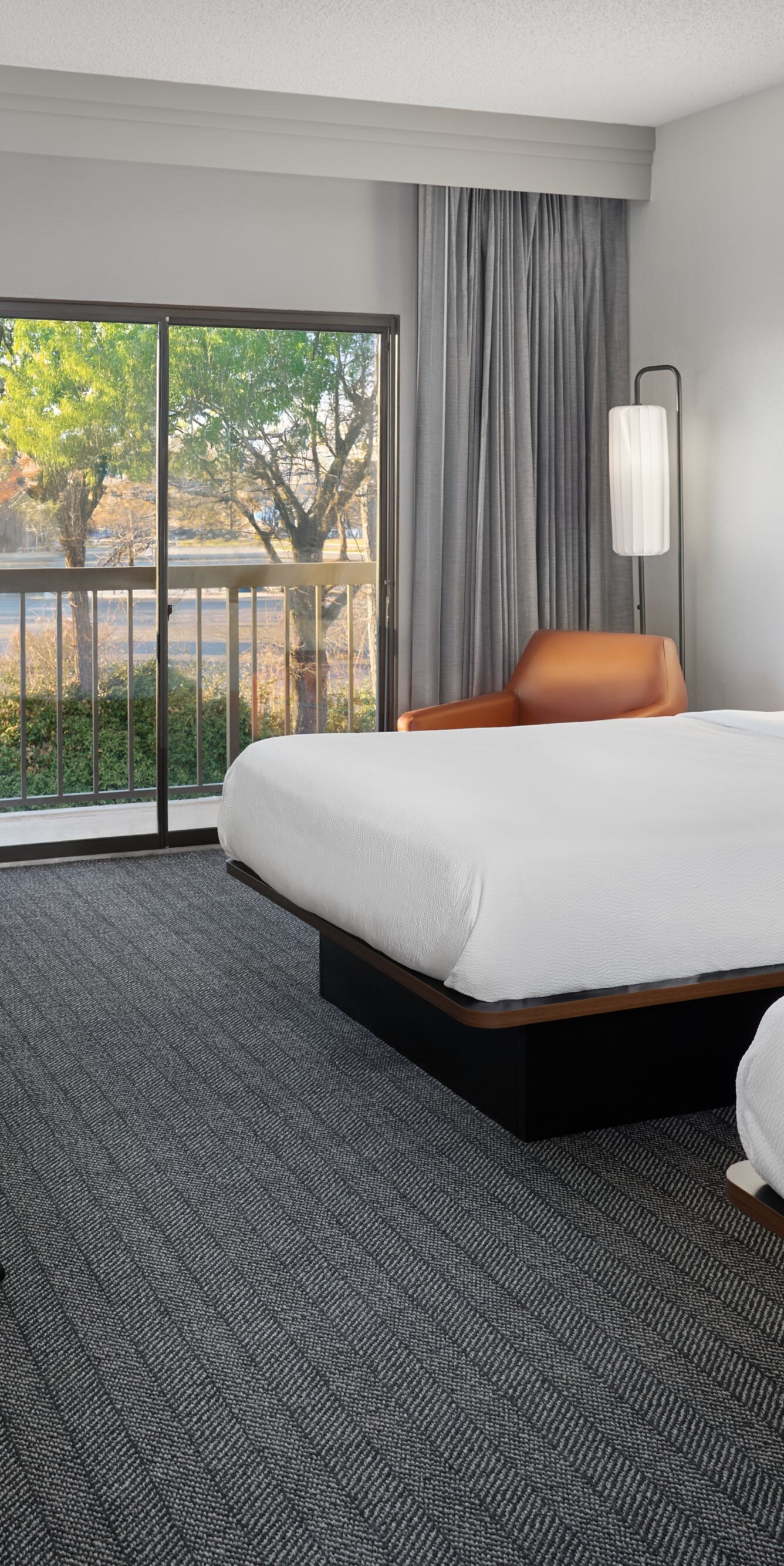 Two queen beds with desk, chair, and balcony view