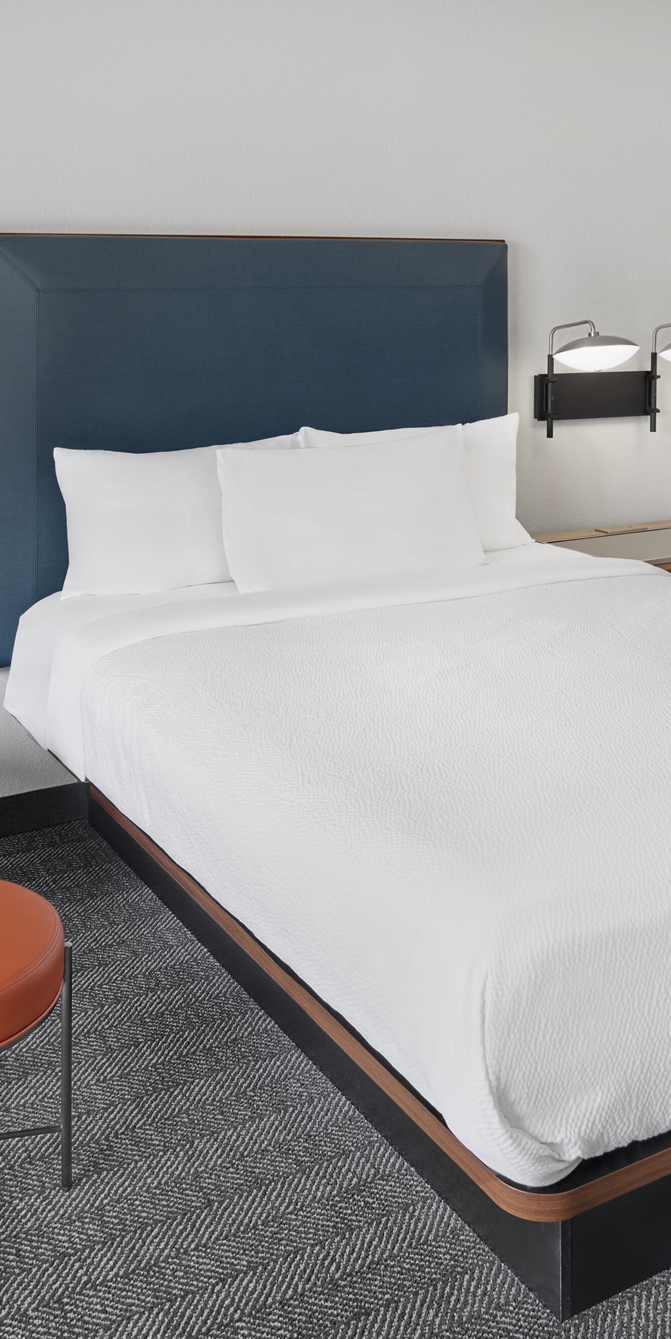 two beds, orange armchair, and ottoman