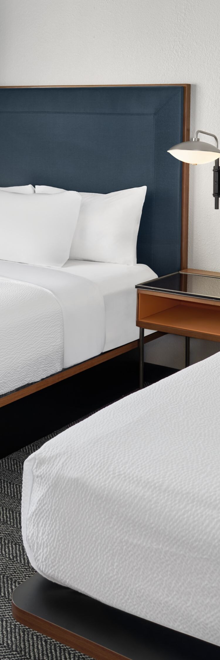 Two beds with blue headboards and window curtains