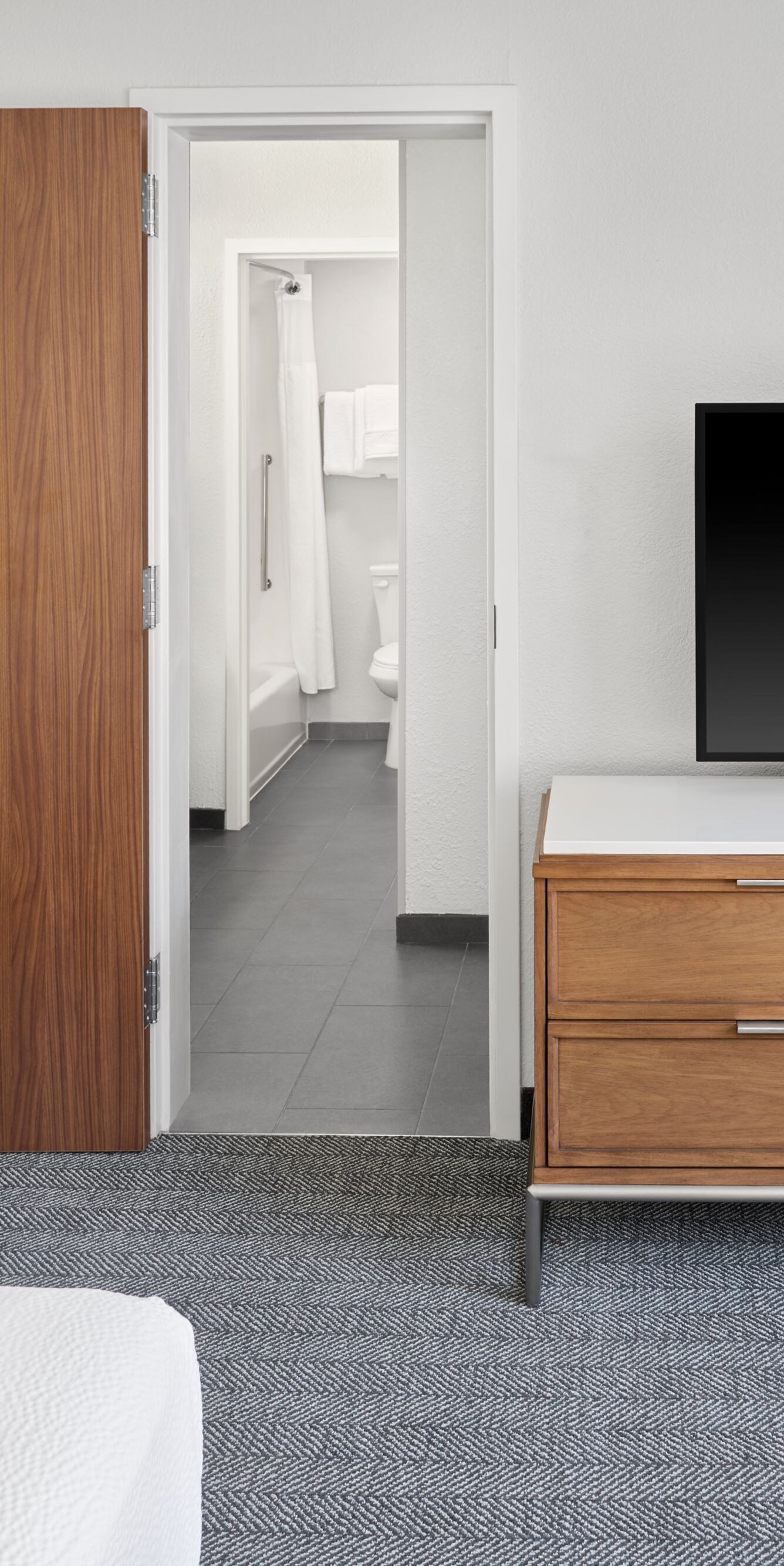 armchair, TV on dresser, and doorway to bathroom