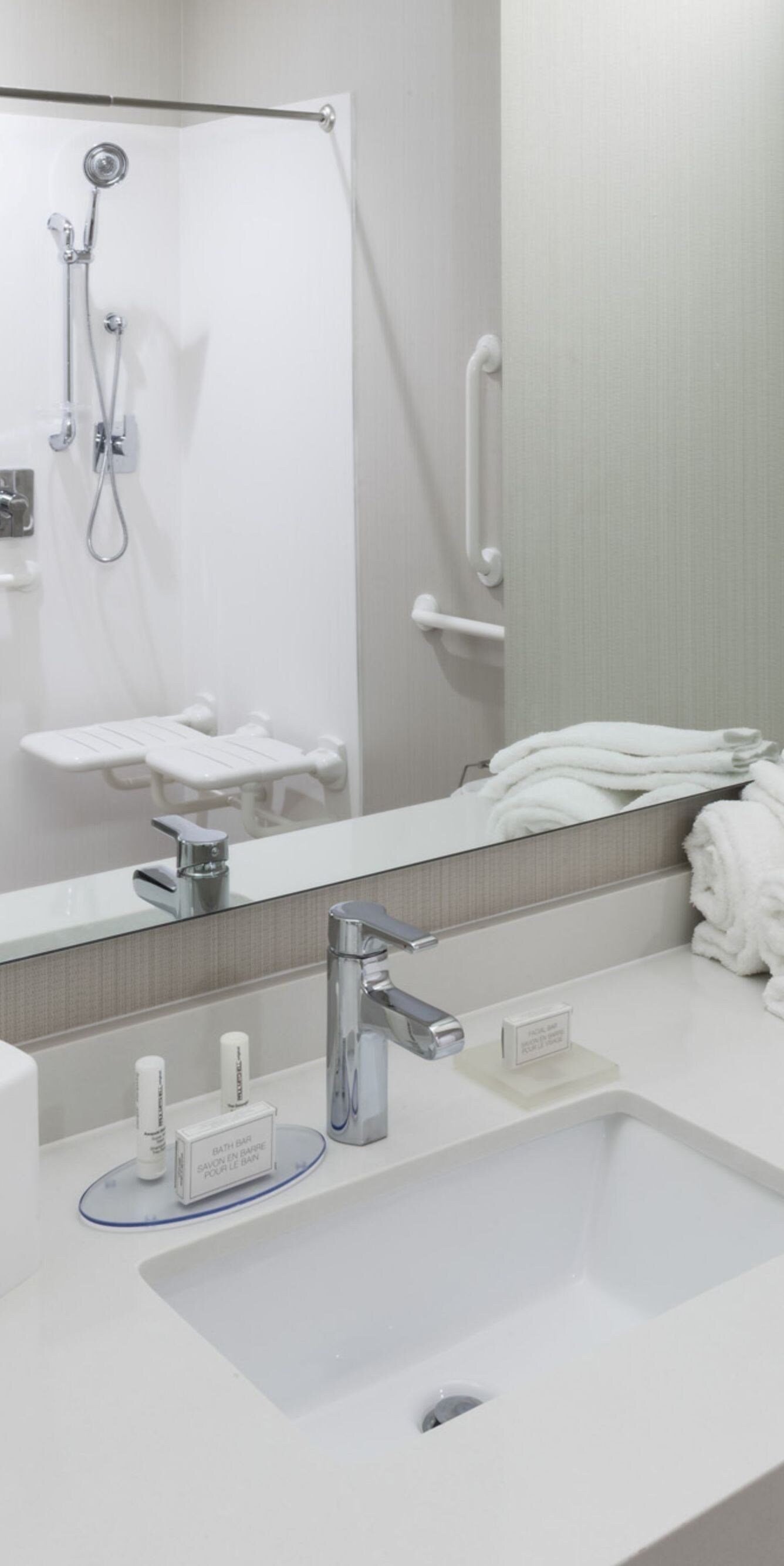 Roll-in shower in reflection of mirror over vanity