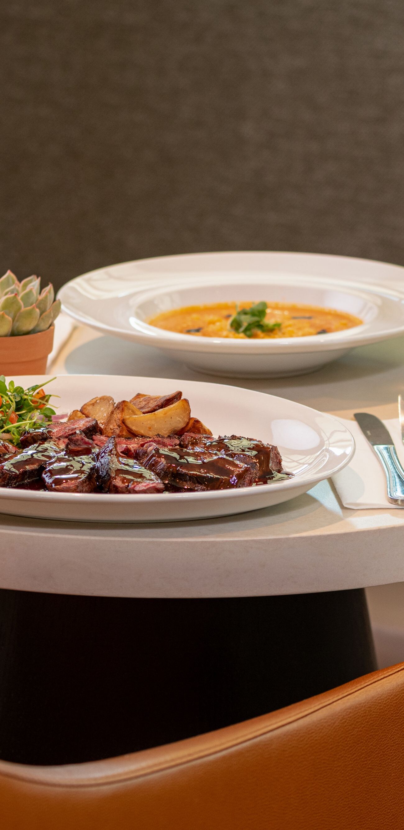 Small table with entree, soup, and two drinks