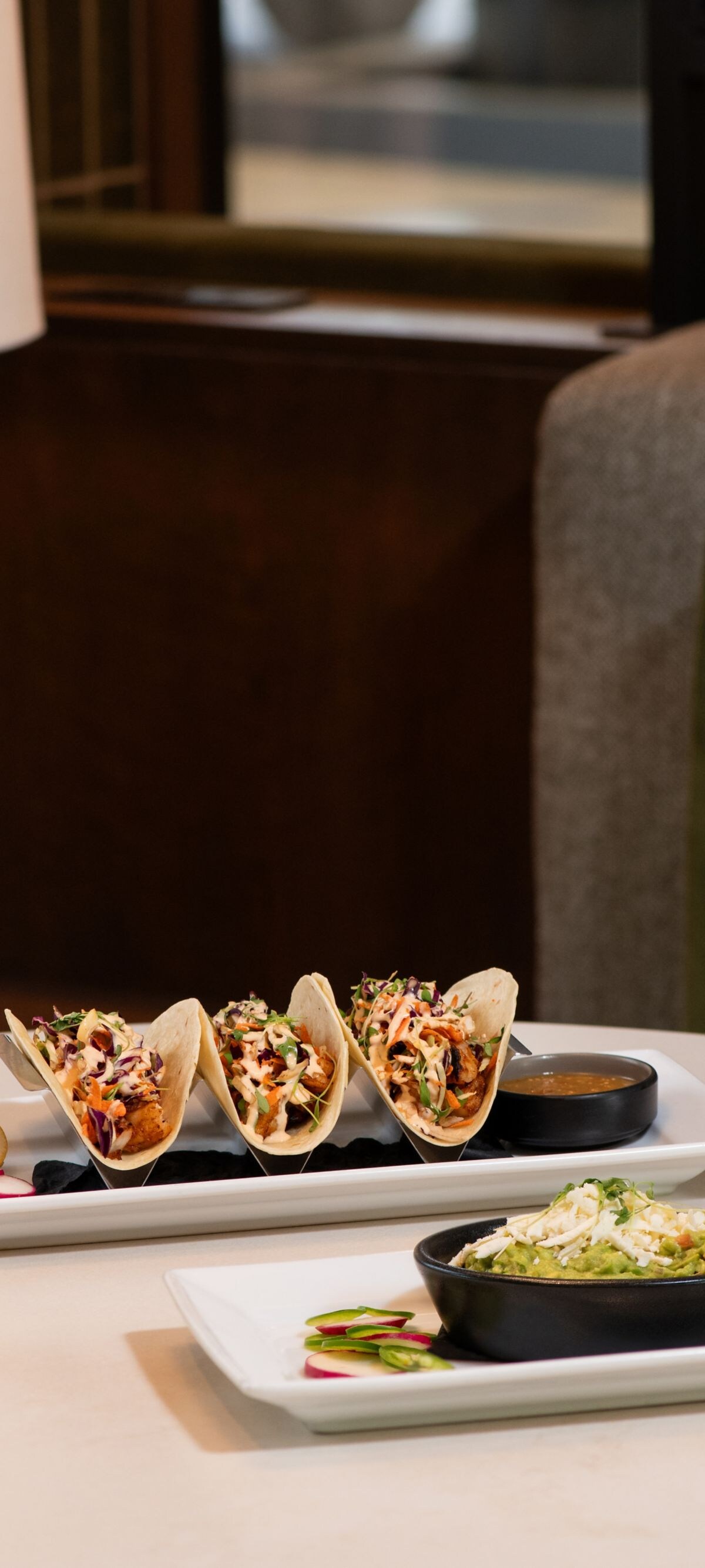Tacos, guacamole, and chips with a beer on table