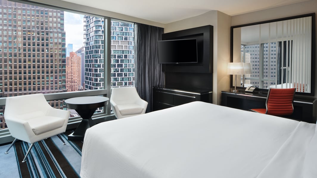 Hotelzimmer mit Kingsize-Bett, 2 Stühlen und Blick auf NYC