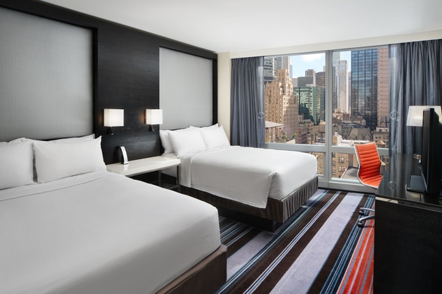 Two double beds with view of NYC buildings.