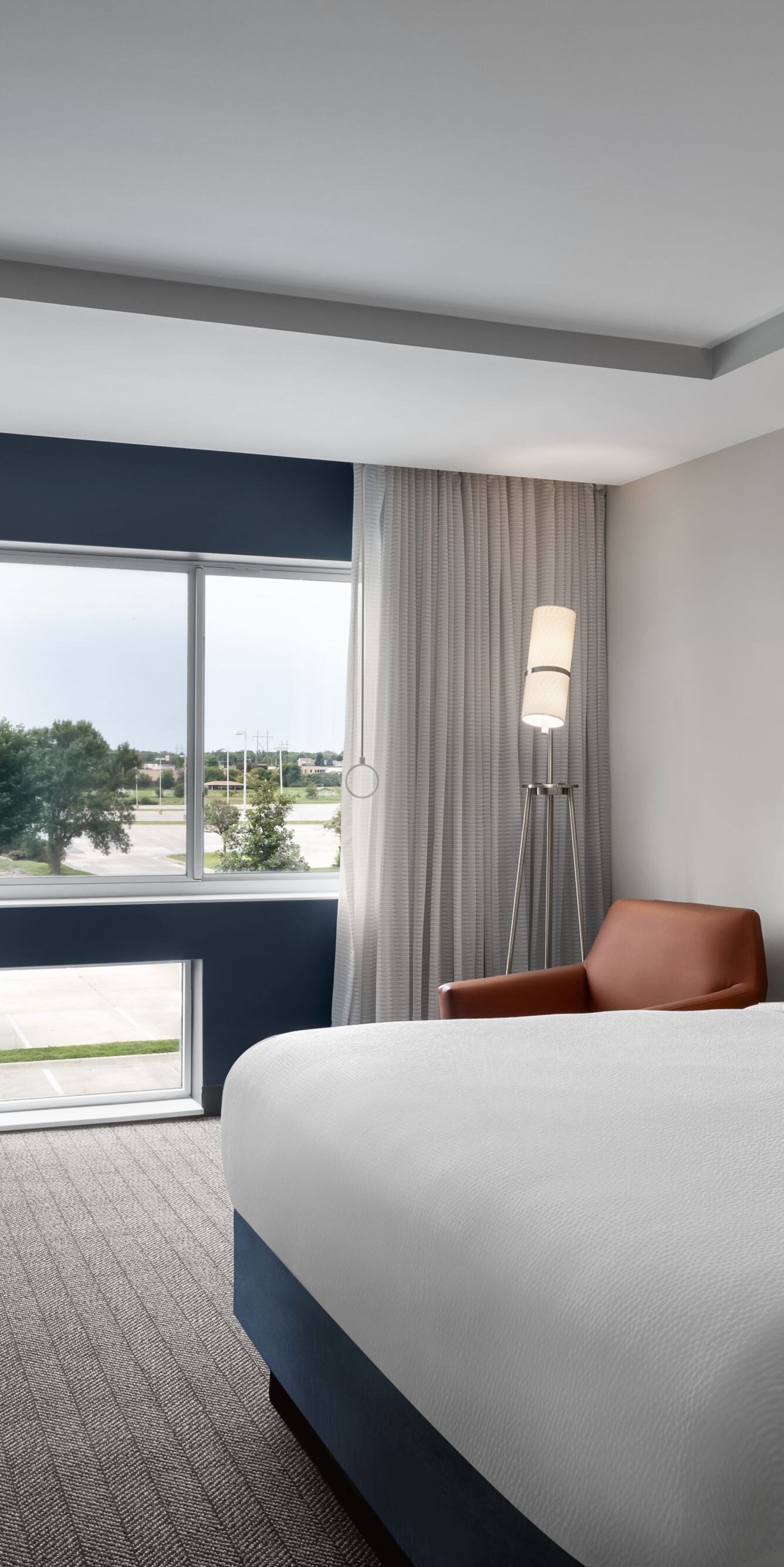 King bed with blue accent wall and window