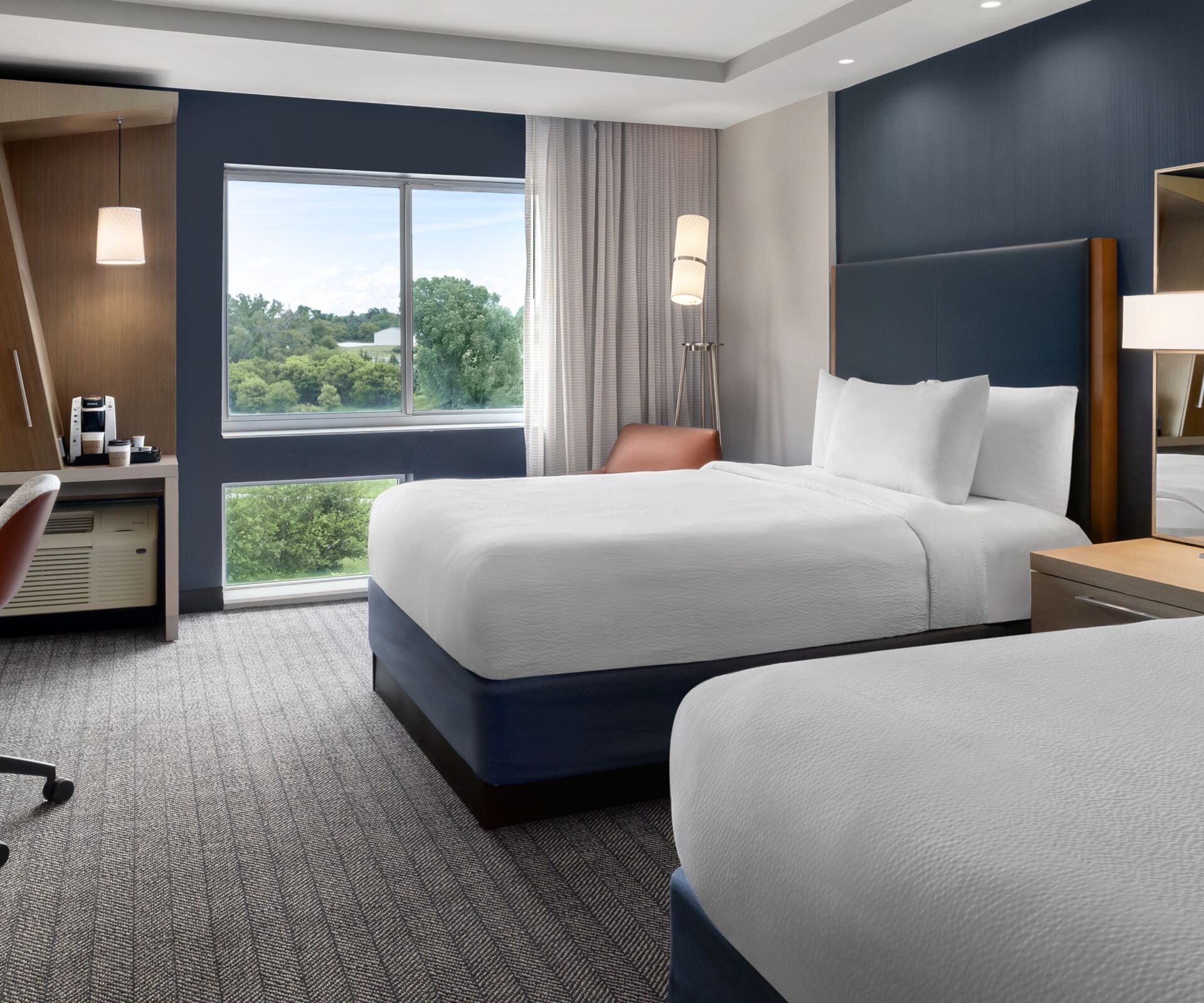 Two queen beds with work desk and window view