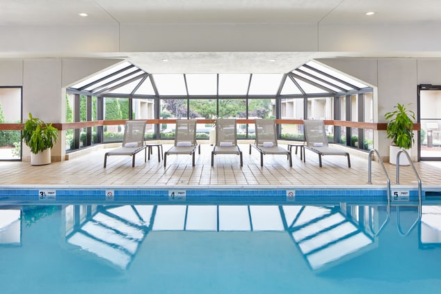 Indoor pool with atrium view and lounge chairs