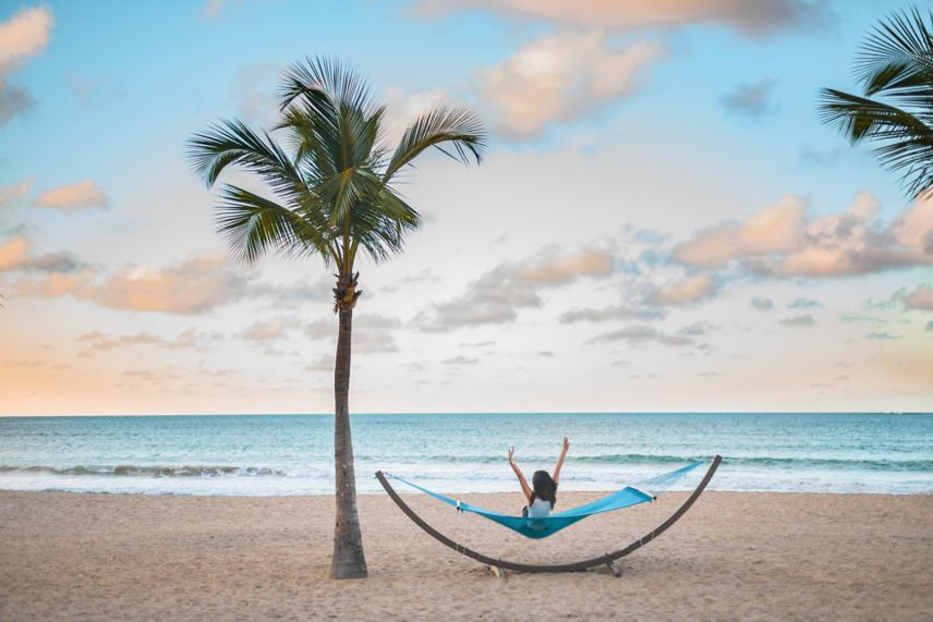 Mujer sentada en una hamaca en la playa
