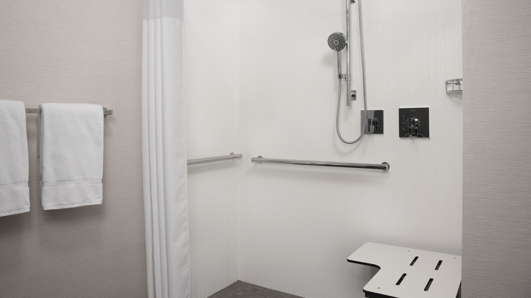 Accessible roll-in shower with grab bars and bench