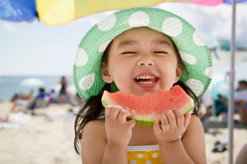 una niña comiendo sandía en la playa
