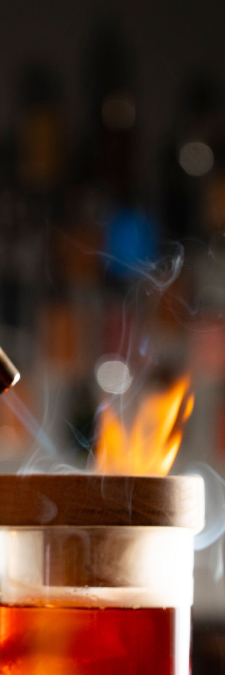 Torch igniting flame atop cocktail glass