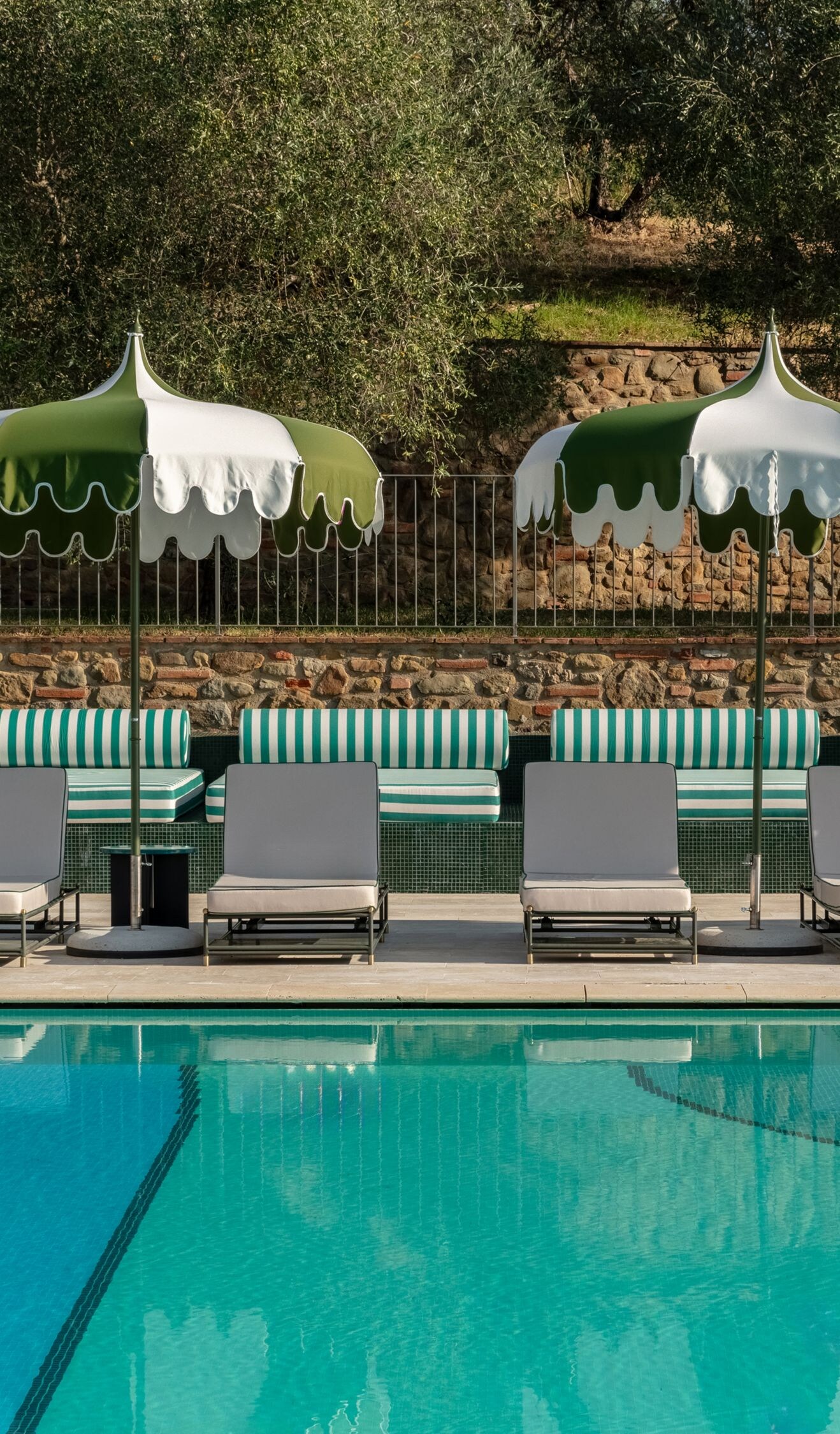 Poolside lounge chairs with green umbrellas