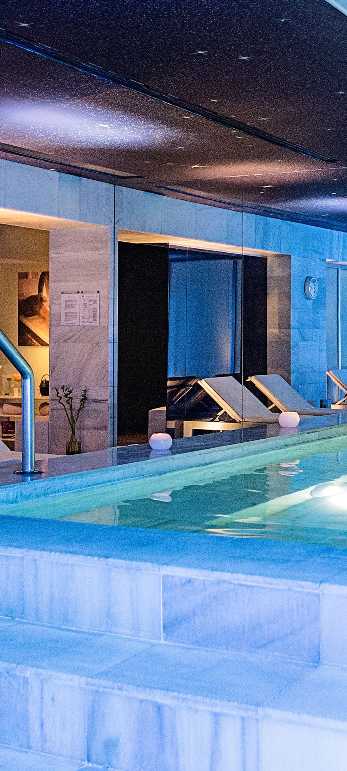 Indoor pool with marble surfaces and loungers