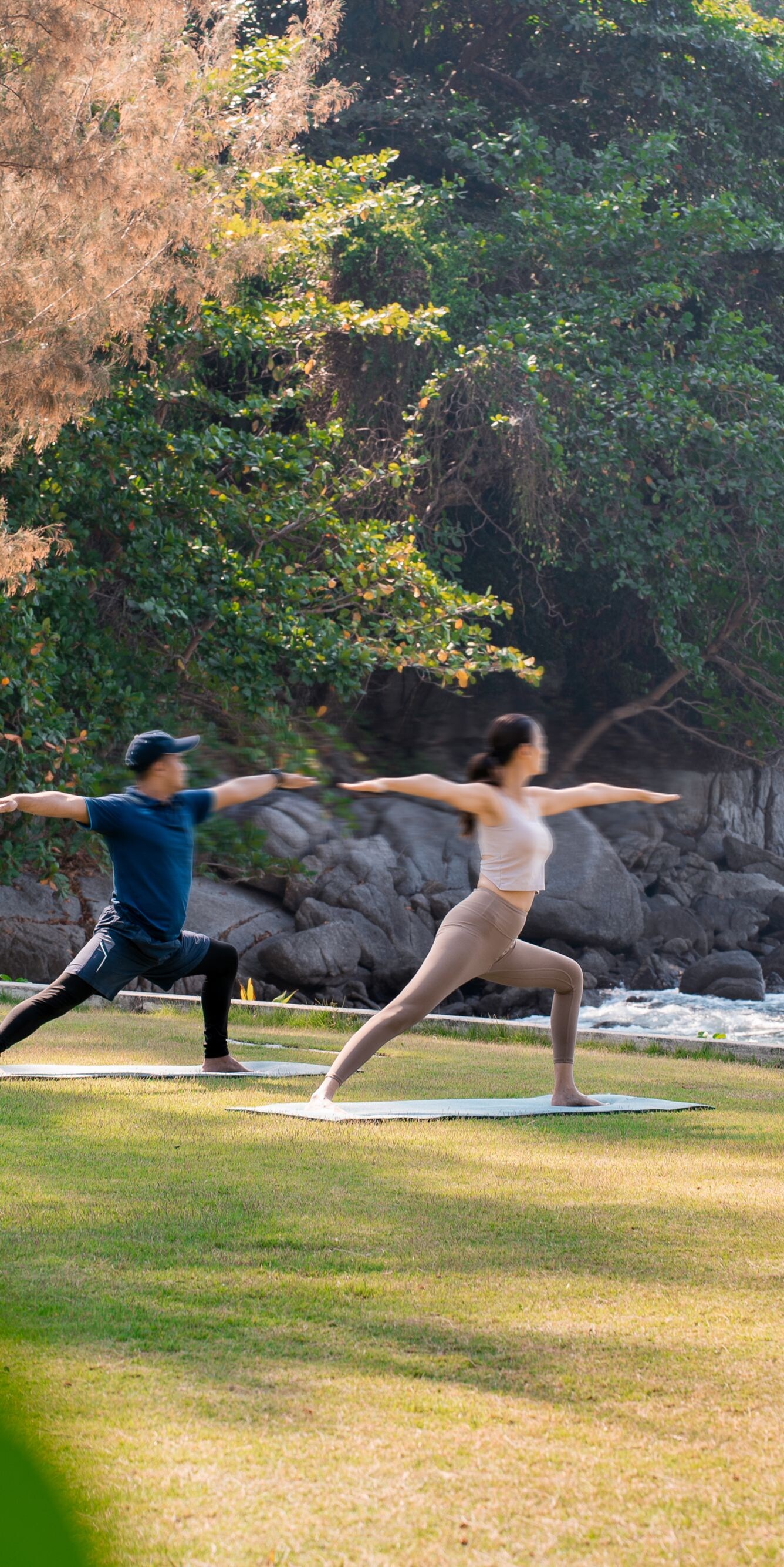 Man and woman doing yoga on the beach