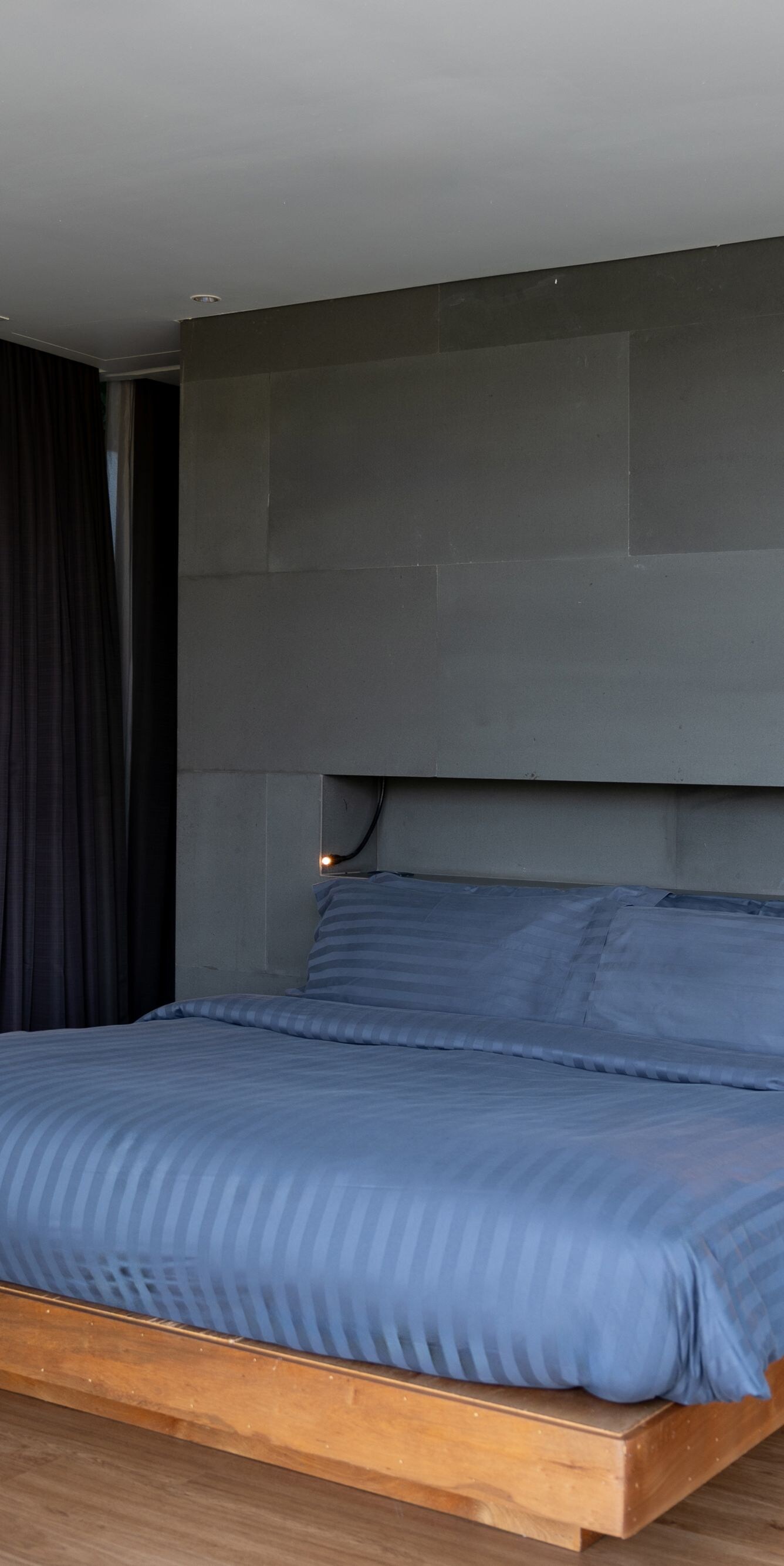 Bedroom with dark gray accent wall, blue bedding