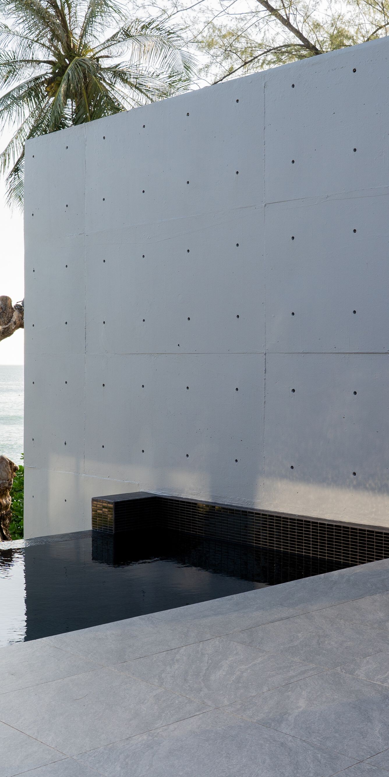 Infinity pool beside gray wall with ocean view