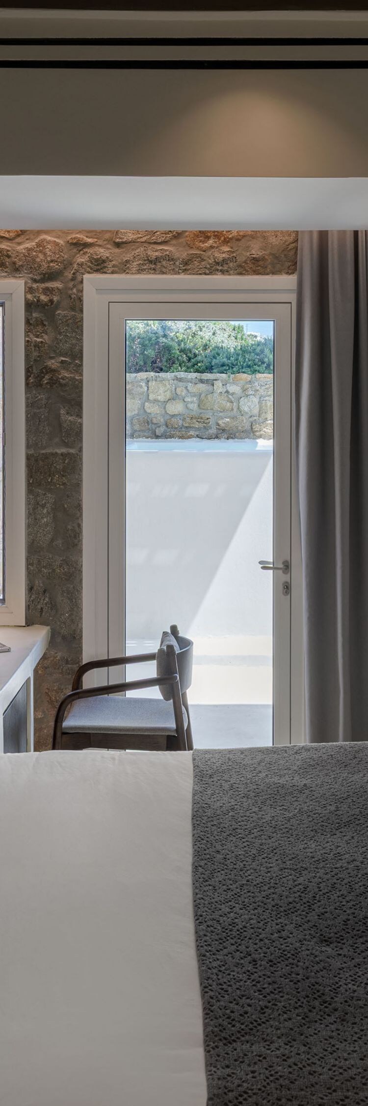 bed, desk with chair, tv, and stone wall