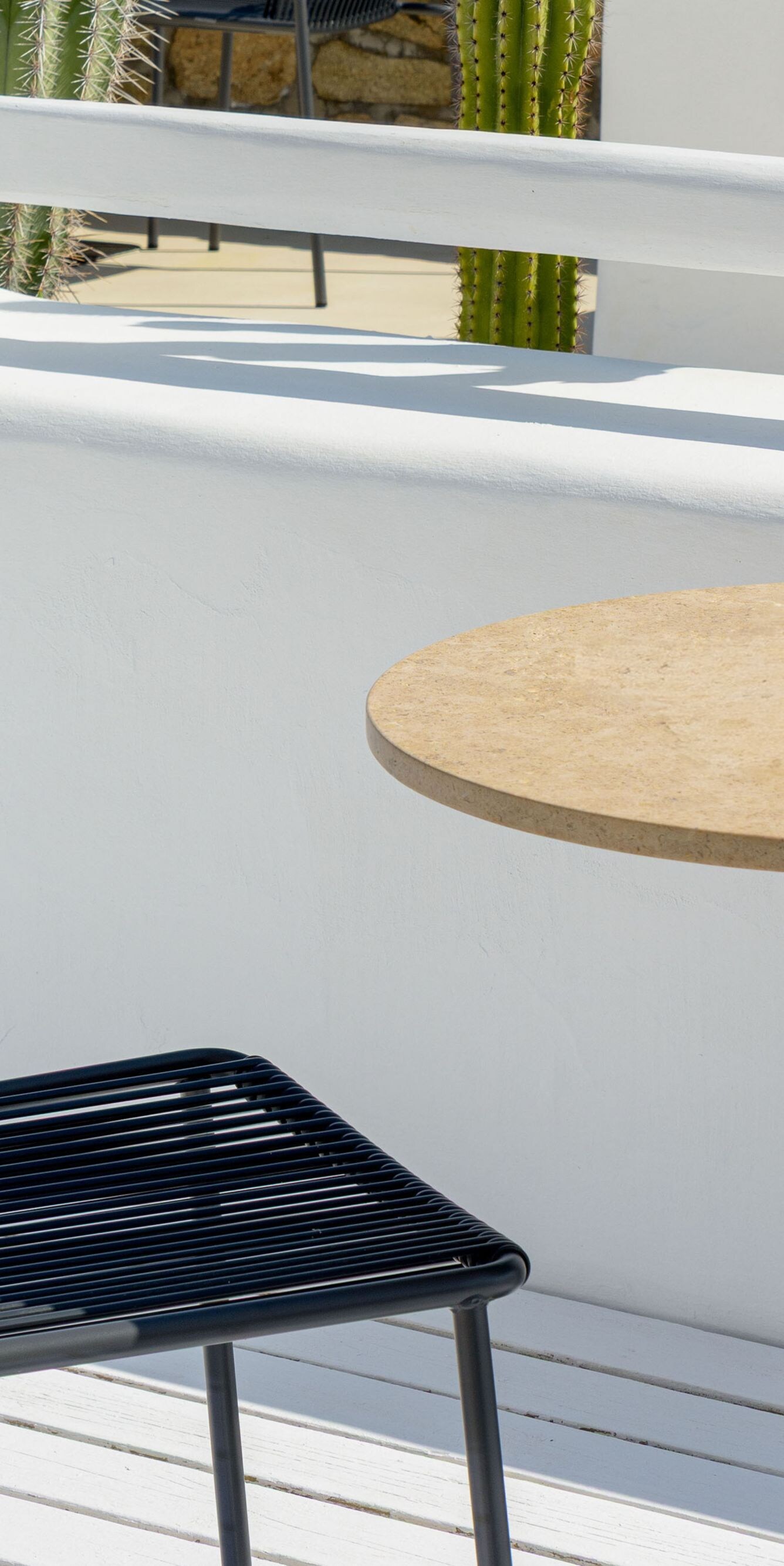Outdoor table and chair by white wall and cactus