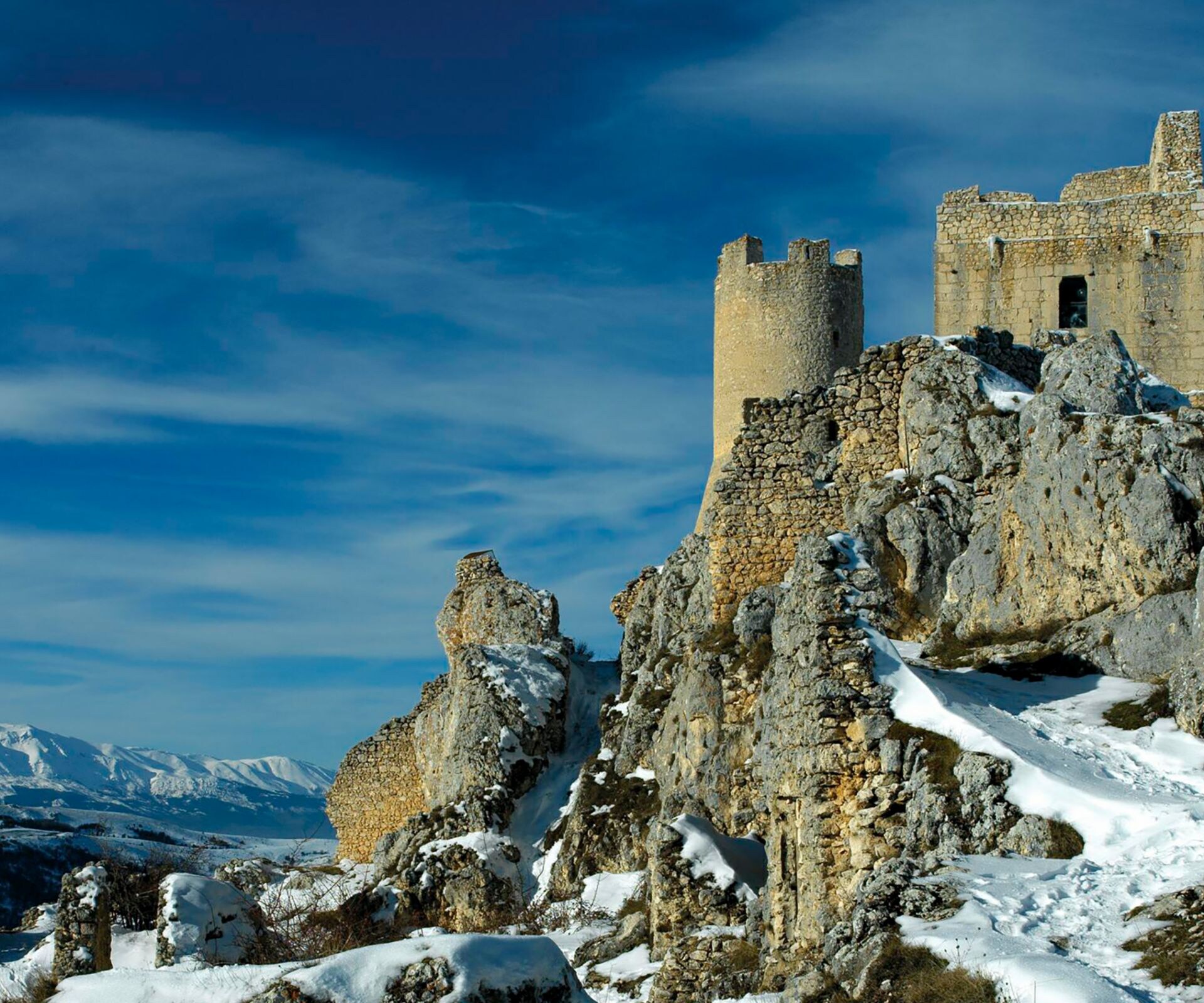 Rovine innevate del castello in pietra sulla cima rocciosa