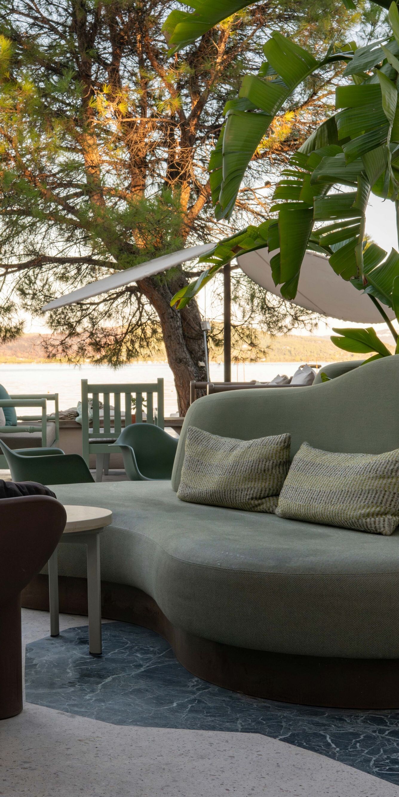 Outdoor lounge seating by water with greenery