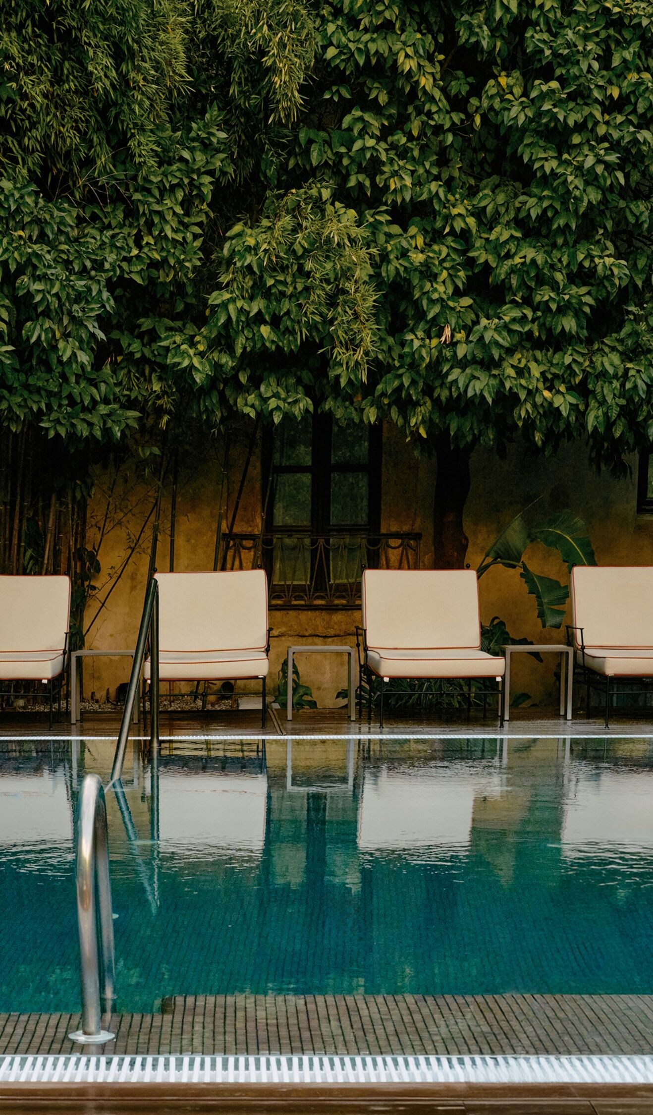 Outdoor pool with lounge chairs and garden