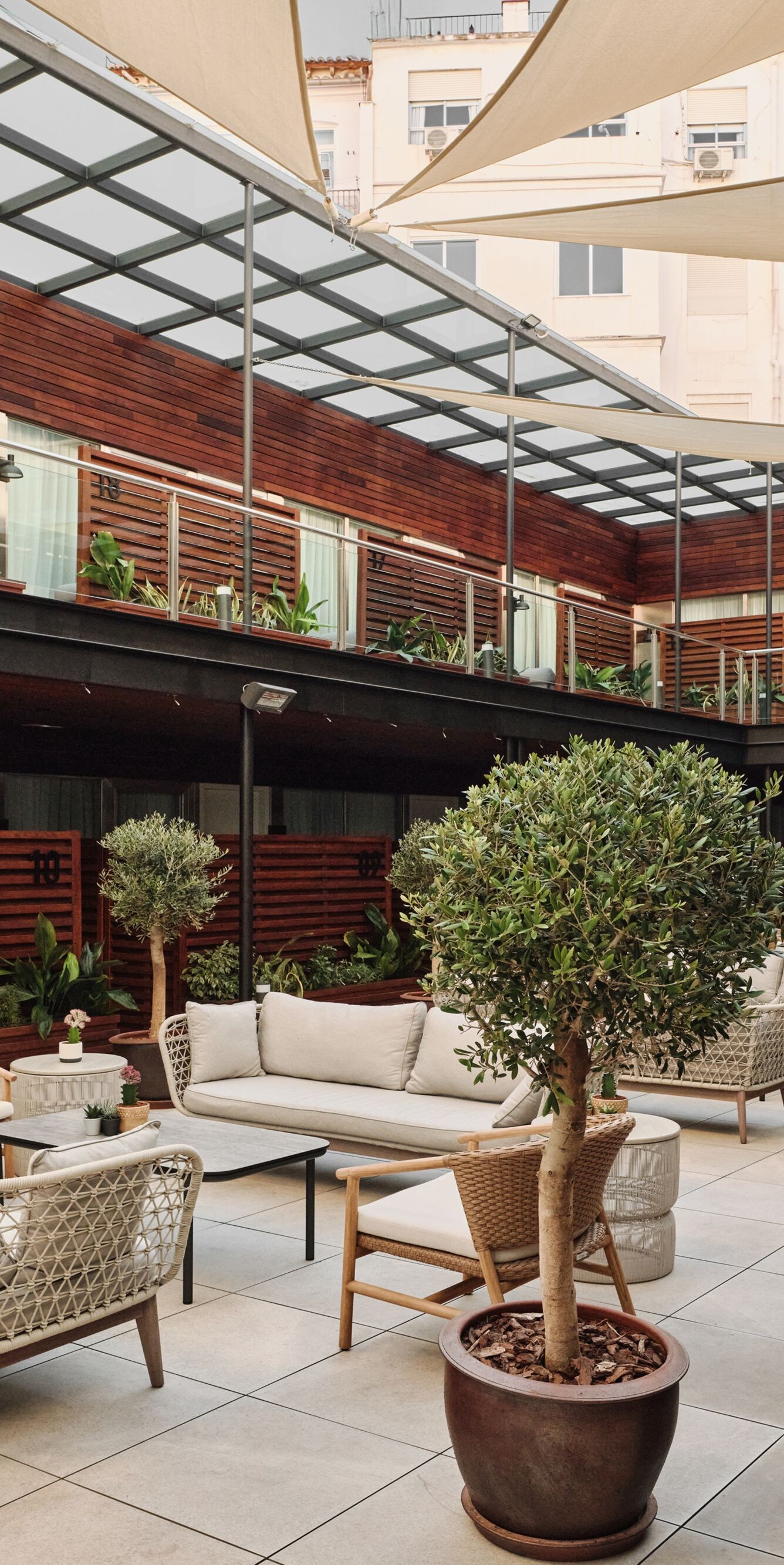 Patio con asientos, mesas y pequeños árboles