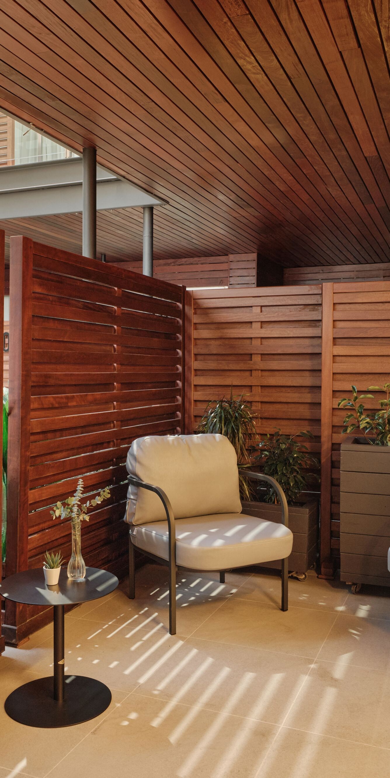 terraza revestida de madera con sillas y una pequeña mesa