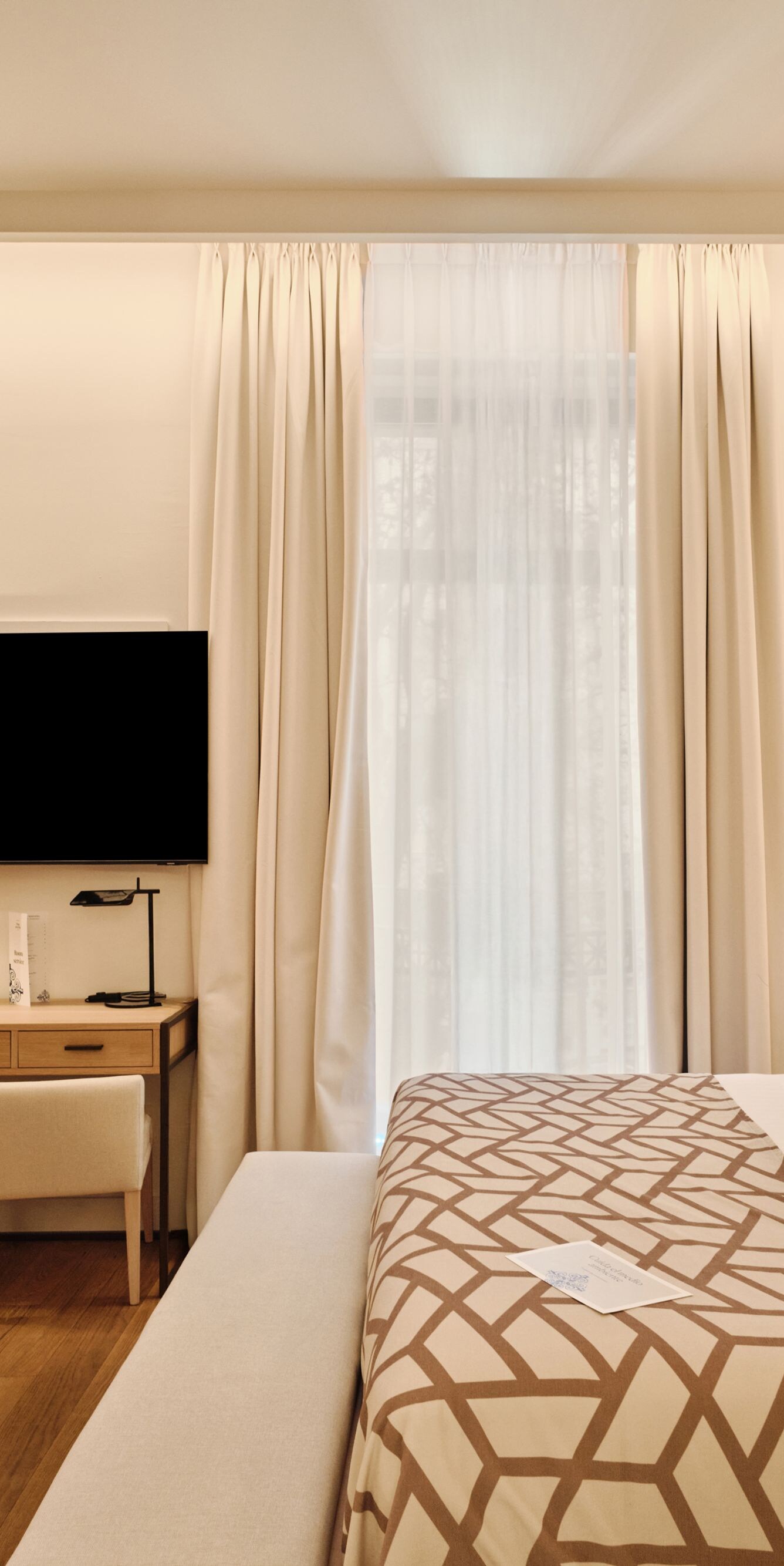 Habitación con cama, televisor, escritorio y ventana