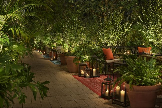 Terrace with lush greenery and candles at night