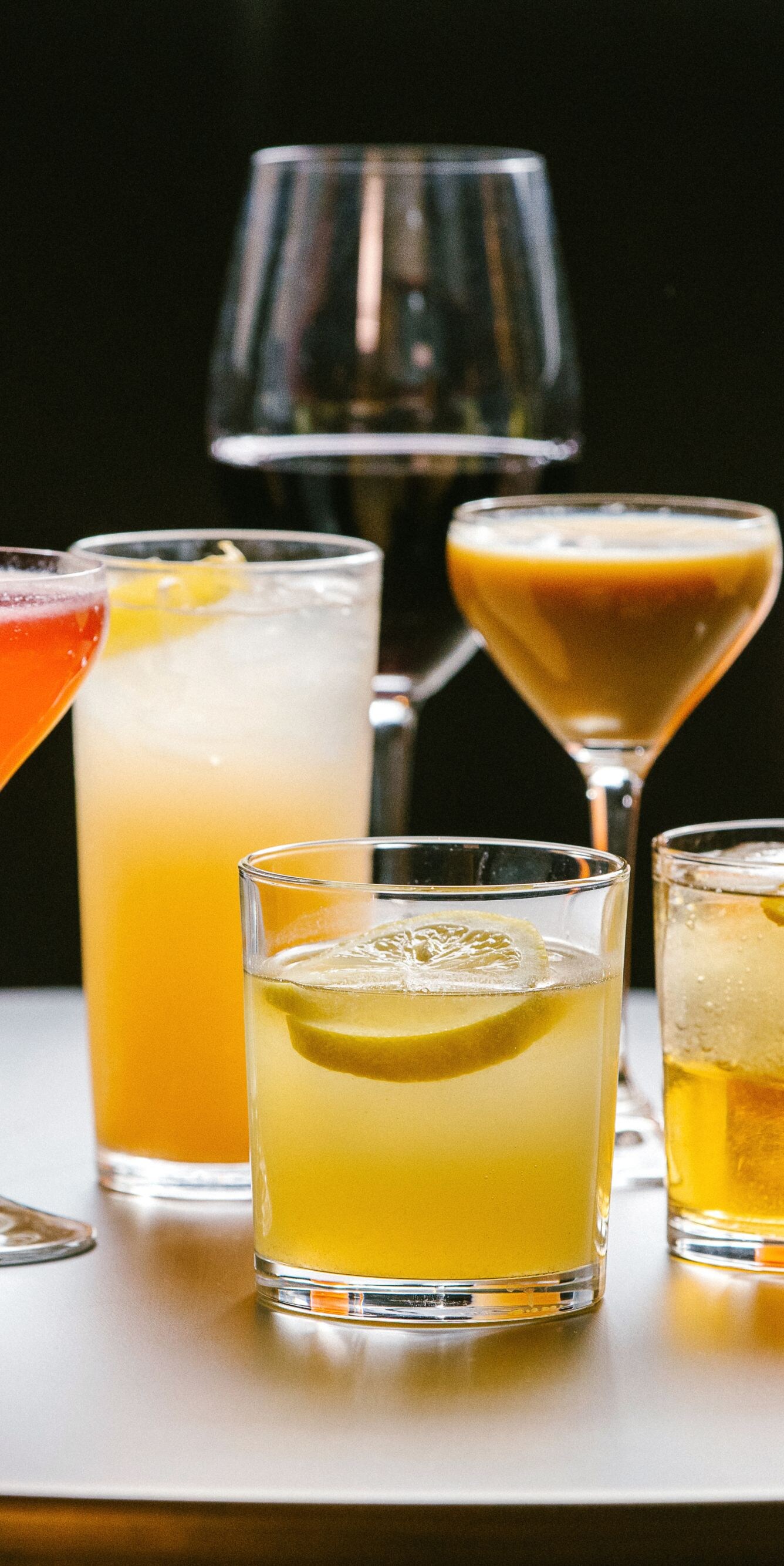 Assorted cocktails on table with citrus garnishes.