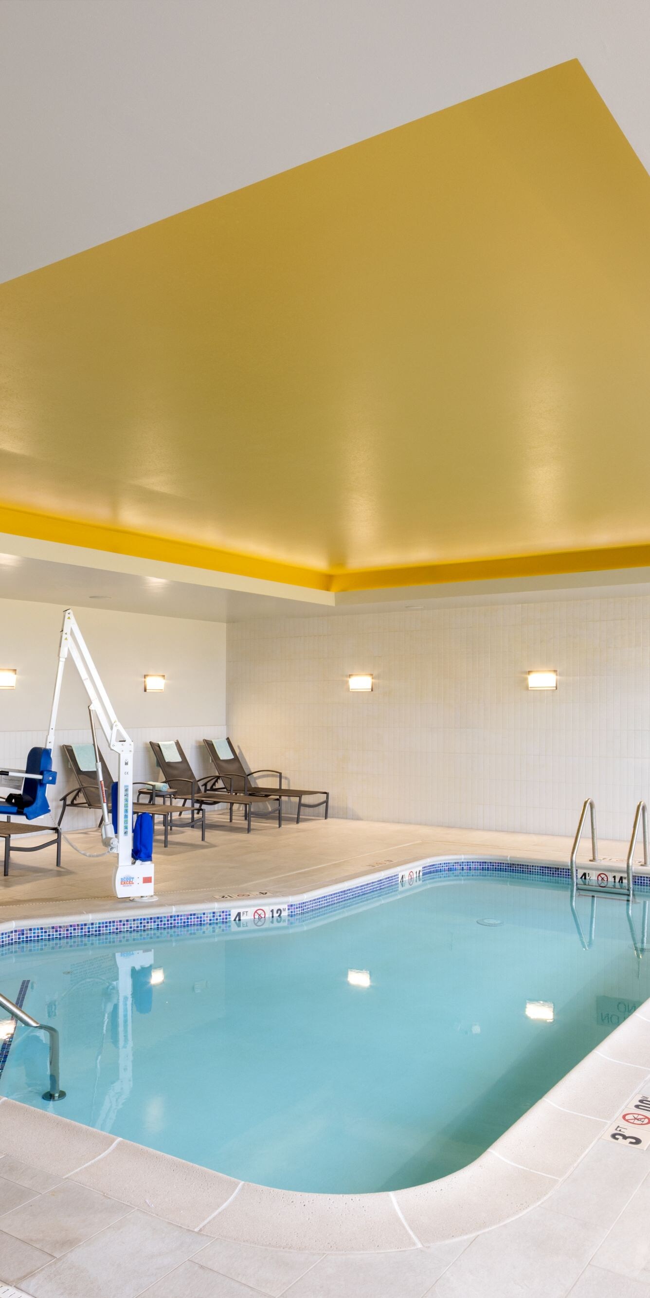 Indoor swimming pool with pool deck and seating.