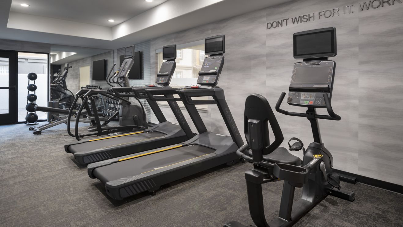 A fitness center with treadmills, elliptical & wei
