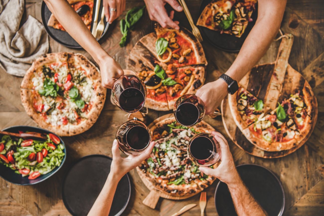 pizza and people celebrating with wine