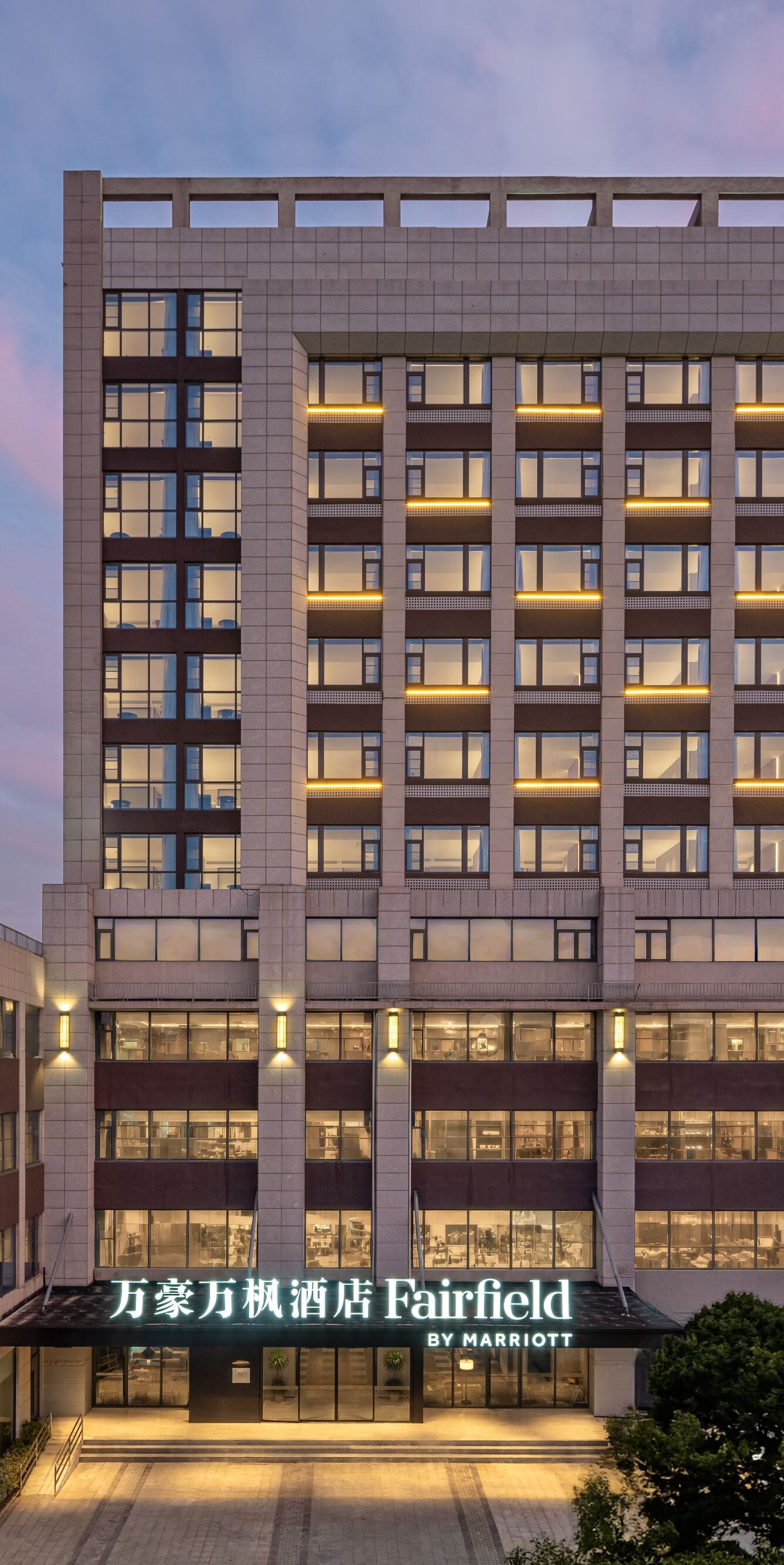 Hotel exterior at dusk with illuminated windows