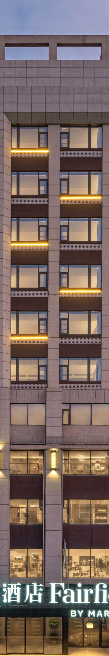 Hotel exterior at dusk with illuminated windows