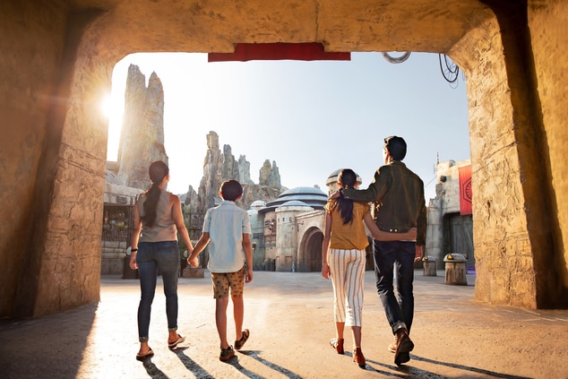 A family of four are walking into a theme park